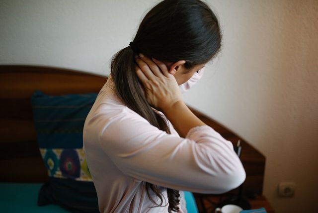 Woman sitting up in bed holding her neck