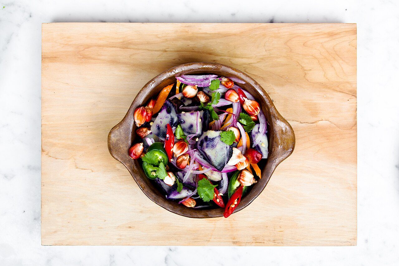 Bowl of mixed vegetable salad on a wooden board
