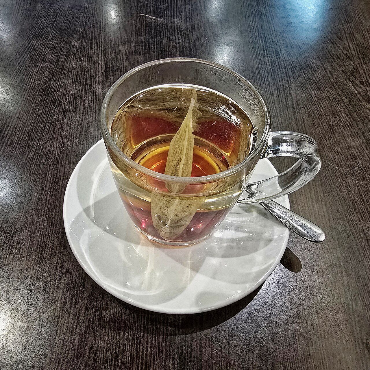 Glass cup of herbal tea on a saucer